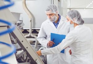 1 male and one female manufacturing professionals checking food product quality in a clean bright facility
